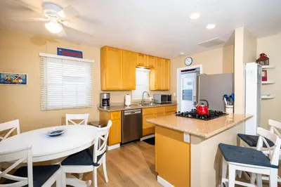 a kitchen and dining room with a table and a counter top at Steps from the Sand Mission Beach House in San Diego