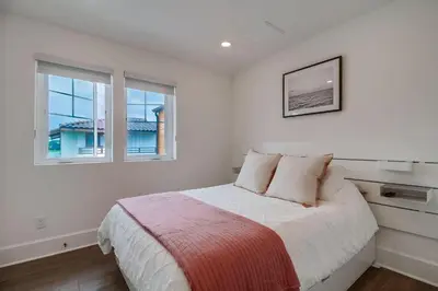 a white bedroom with a bed and two windows at Bayside Cove 10 in San Diego