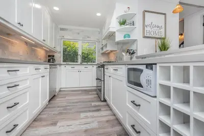 a kitchen with white cabinets and a wooden floor at Seaside Retreat in San Diego