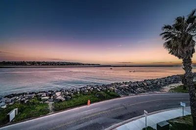a view of the beach at sunset with a palm tree at Ocean Vista Penthouse 1 in San Diego