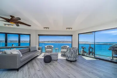 a living room with a couch and chairs and windows at Ocean Vista Penthouse 1 in San Diego