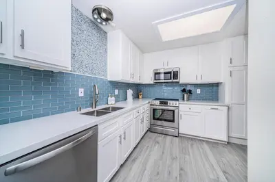 a kitchen with white cabinets and blue tiles at Ocean Vista Penthouse 1 in San Diego