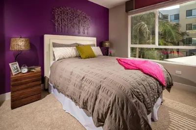 a bedroom with a bed with purple walls and a window at Ariva in San Diego
