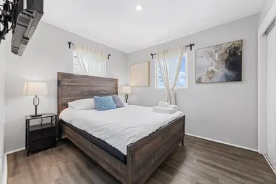 a bedroom with a large bed and two windows at Charming Gem in LH, High Speed WiFi Minutes from Beach, Downtown & Petco Park! in San Diego