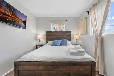 a bedroom with a bed with white sheets and blue pillows at Charming Gem in LH, High Speed WiFi Minutes from Beach, Downtown & Petco Park! in San Diego