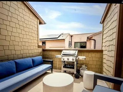 a patio with a blue couch and a grill at Beach Bloom in San Diego