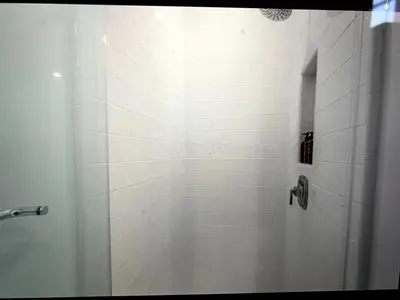 a bathroom with a shower with white tiles at Beach Bloom in San Diego