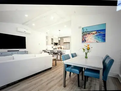 a living room with a white couch and a table and chairs at Beach Bloom in San Diego