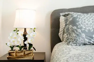 a bed with a lamp and flowers on a night stand at Modern 2BR Near Petco Park & Convention Center in San Diego