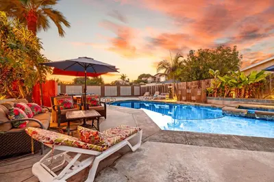 a swimming pool with patio furniture and an umbrella at Boho Oasis with Pool Spa Firepit BBQ Ping Pong in San Diego