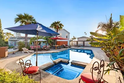 a swimming pool with two chairs and an umbrella at Boho Oasis with Pool Spa Firepit BBQ Ping Pong in San Diego