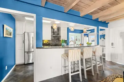 a kitchen with blue walls and a bar with stools at Boho Oasis with Pool Spa Firepit BBQ Ping Pong in San Diego