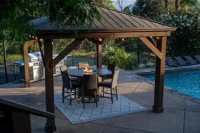 a wooden pavilion with a table and chairs next to a pool at Mountain Villa in San Diego - Pool & Waterslide, Spa, Pickle Ball, Game room in La Mesa