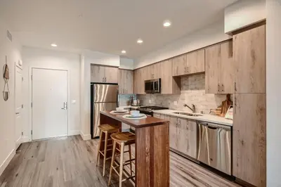 a kitchen with wooden cabinets and a counter with stools at Vive Luxe in San Diego
