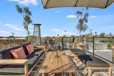 a patio with a couch and tables on a roof at European Charm Meets La Jolla Rooftop Views in San Diego