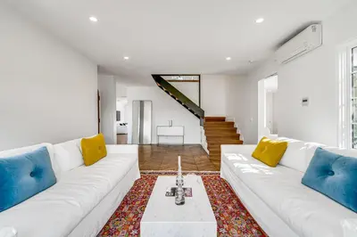 a white living room with a white couch and yellow pillows at European Charm Meets La Jolla Rooftop Views in San Diego