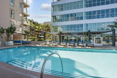 a swimming pool with chairs and a building at Vive on The Park in San Diego