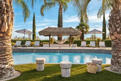 a pool with chairs and a gazebo and palm trees at Villa Verdot 6BR Estate w Pool Tennis Basketball in Temecula