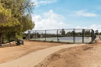 a tennis court behind a fence with a bench at Villa Verdot 6BR Estate w Pool Tennis Basketball in Temecula