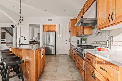 a kitchen with wooden cabinets and a stainless steel refrigerator at Villa Verdot 6BR Estate w Pool Tennis Basketball in Temecula