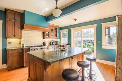 a kitchen with blue walls and a large island with stools at Gorgeous Eccentric Family Home with Cowboy Pool in San Diego