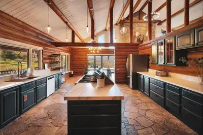 a large kitchen with black cabinets and a refrigerator at Red Hawk Ridge SD Mag Design Winner in Alpine