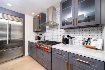 a kitchen with blue cabinets and a stainless steel refrigerator at Fallbrook Hilltop Sanctuary - Pool & Pickleball in Fallbrook