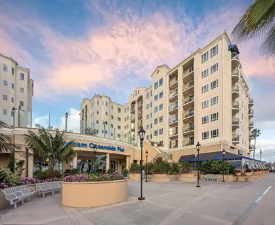 a large building with a courtyard in front of it at Wyndham Oceanside Pier 2BR Apartment with Resort Access in Oceanside