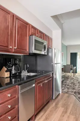a kitchen with wooden cabinets and a stainless steel refrigerator at Wyndham Harbour Lights Studio Apartment with Resort Access in San Diego