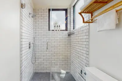 a white bathroom with a shower and a window at Sea & Stroll Abode in Carlsbad