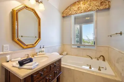 a bathroom with a tub and a sink and a mirror at Fountainhead Vineyards Manor in Temecula