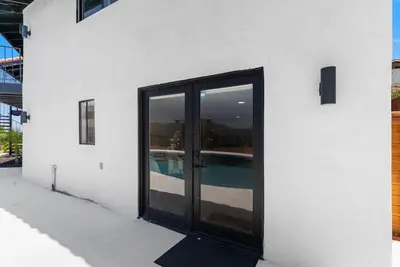 a white building with glass doors and a swimming pool at Sunset house in El Cajon