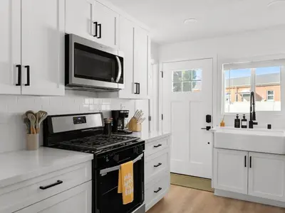 a white kitchen with a stove and a microwave at Barrio Casita - 2Bd, Central, Parking, EV Charging in San Diego