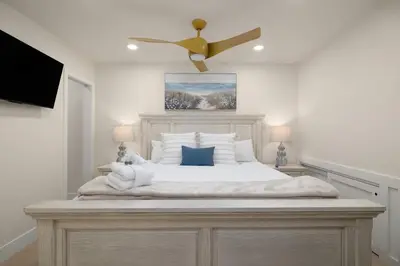 a bedroom with a large white bed with a ceiling fan at The 357 Beach Pad, Renovated, Refined, Steps from the Surf! in San Diego