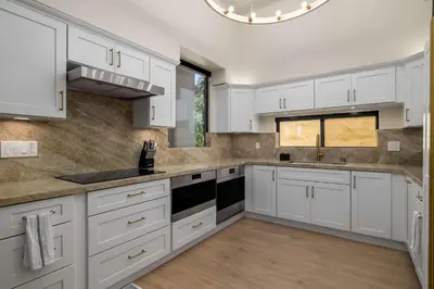 a white kitchen with white cabinets and a window at The 357 Beach Pad, Renovated, Refined, Steps from the Surf! in San Diego