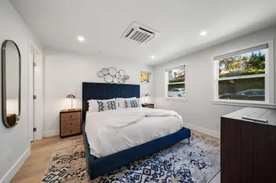 a bedroom with a blue bed and two windows at La Jolla Panoramic Ocean Retreat with Rooftop in San Diego