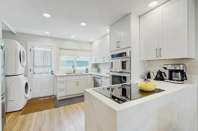 a kitchen with white cabinets and a white refrigerator at Bayview Serenity Oceanfront in San Diego