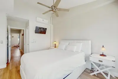 a white bedroom with a white bed and a ceiling fan at Bayview Serenity Oceanfront in San Diego