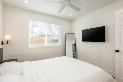 a white bedroom with a bed and a flat screen tv at Modern home near Downtown San Diego in San Diego