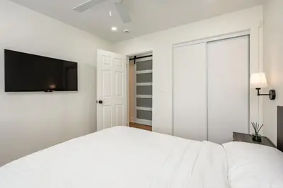 a bedroom with a white bed and a flat screen tv at Modern home near Downtown San Diego in San Diego