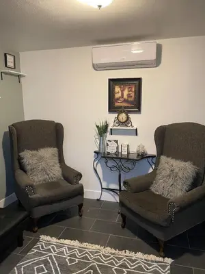 a living room with two chairs and a fan at Oasis Resort in Homeland