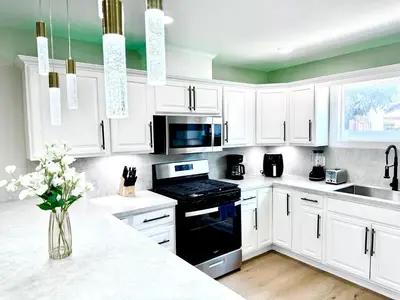 a kitchen with white cabinets and a black stove top oven at Xlnc Exotic home Poway in Poway