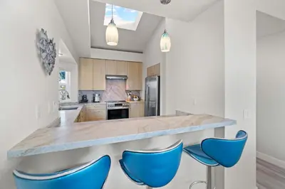 a kitchen with blue chairs at a counter at Carlsbad Retreat by the Sea -30-Night Minimum in Carlsbad