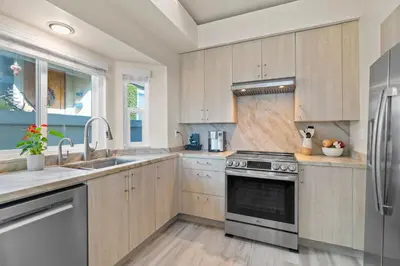 a kitchen with wooden cabinets and stainless steel appliances at Carlsbad Retreat by the Sea -30-Night Minimum in Carlsbad
