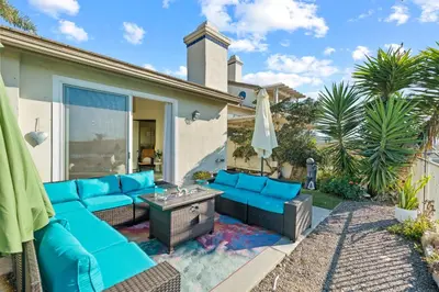 a patio with blue couches and an umbrella at Carlsbad Retreat by the Sea -30-Night Minimum in Carlsbad