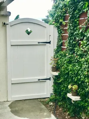 a white gate in front of a hedge with plants at Classic Laguna Cottage in Laguna Beach