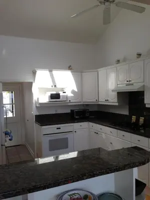a kitchen with white cabinets and a stove top oven at Classic Laguna Cottage in Laguna Beach