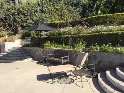 two chairs and an umbrella on a patio at Classic Laguna Cottage in Laguna Beach
