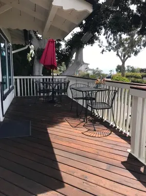 a deck with tables and chairs and an umbrella at Classic Laguna Cottage in Laguna Beach