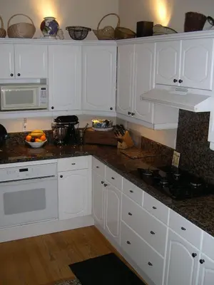 a kitchen with white cabinets and granite counter tops at Classic Laguna Cottage in Laguna Beach